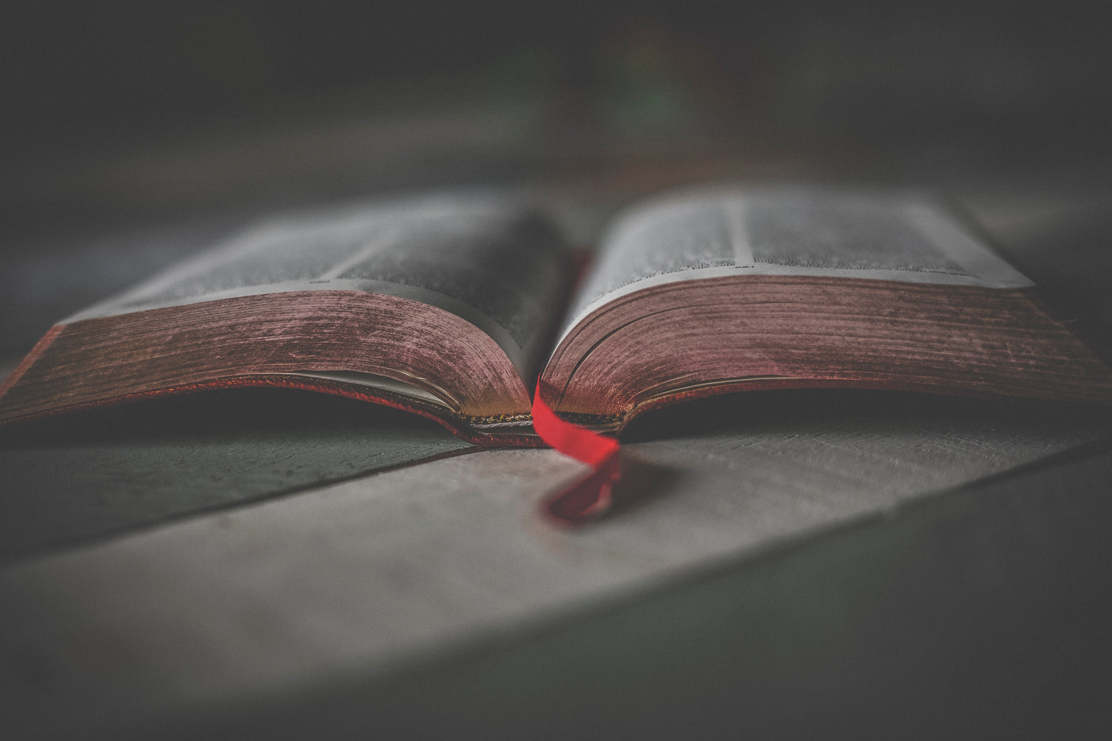 a religious book open to the middle on a table with a red ribbon marking the page