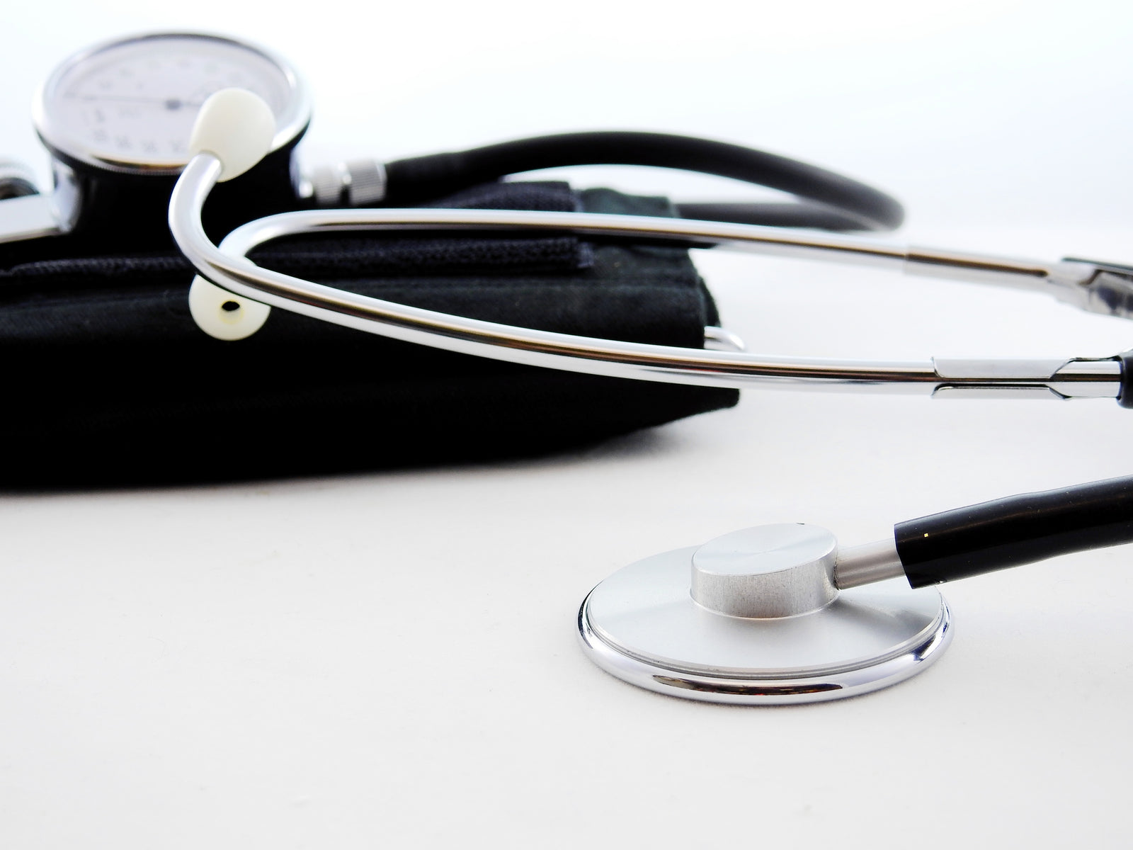 closeup of stethoscope and blood pressure cuff on white surface