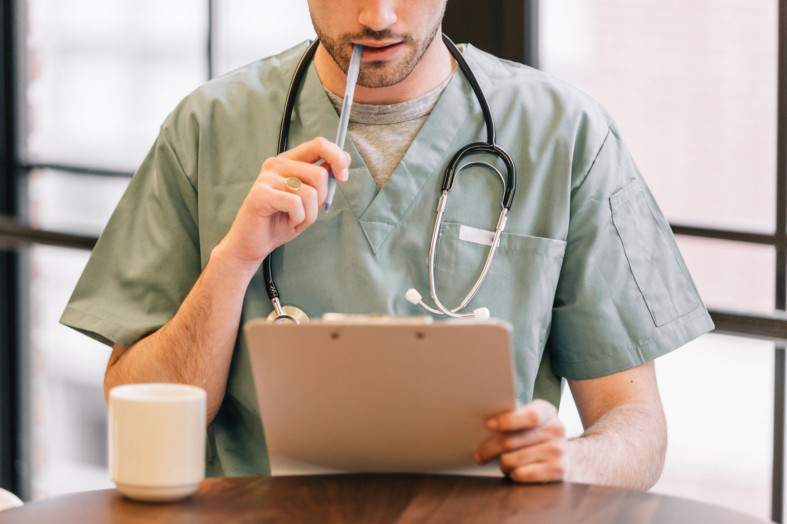 Male RPN in scrubs looking at clipboard